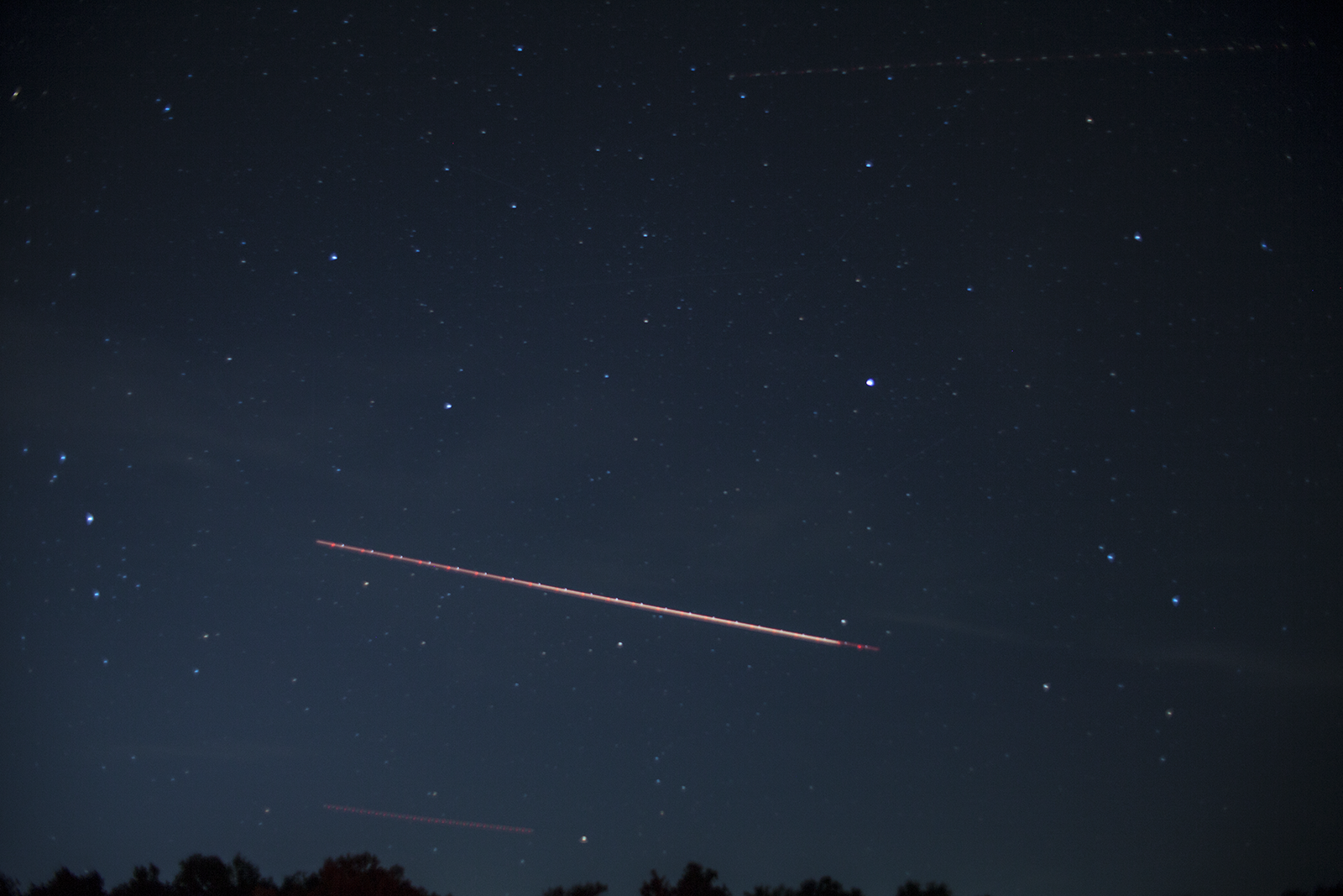 Star field looking east with aircraft trail and treeline